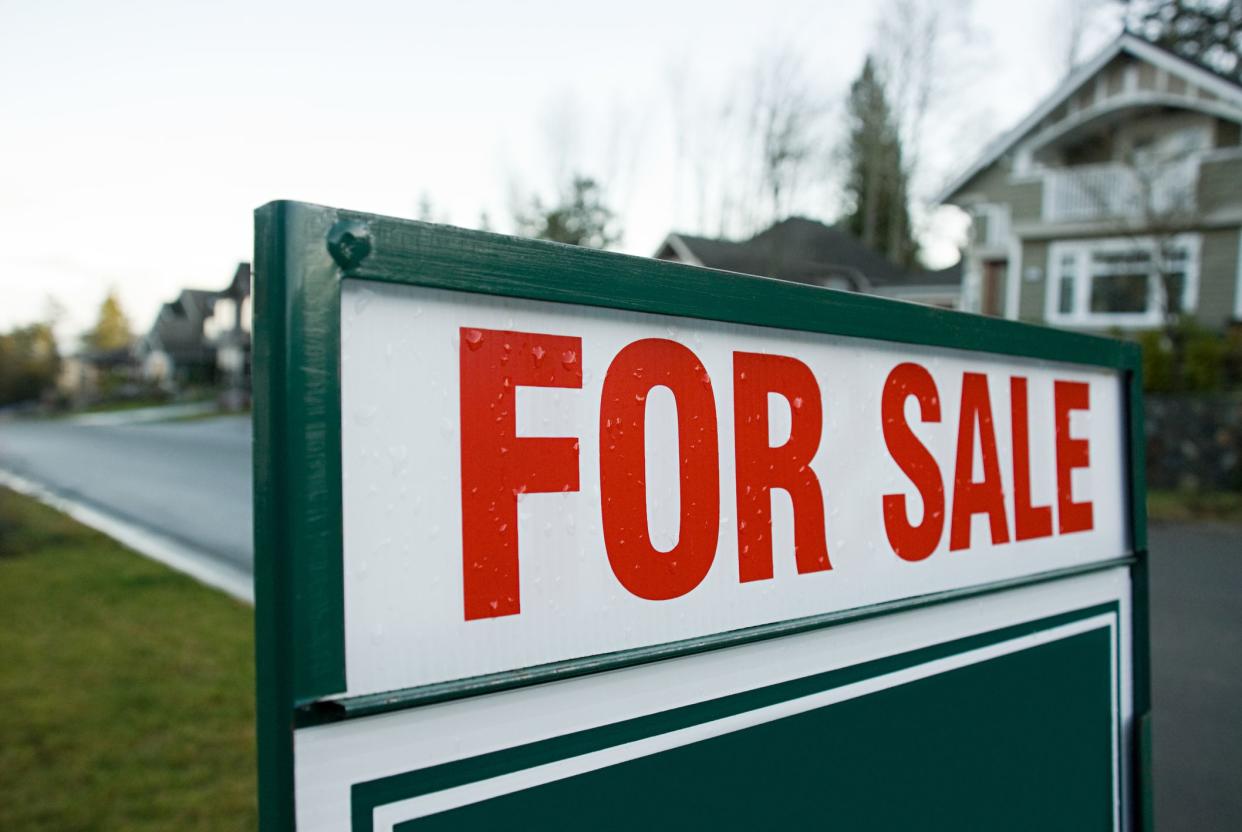 home 'For Sale' sign in front yard of home in a suburb that had a slight rain shower