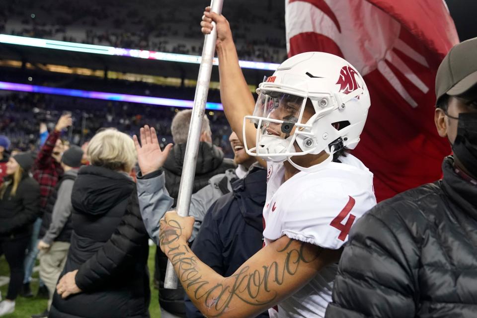 Washington State quarterback Jayden de Laura carries a Cougar flag on the field after WSU defeated Washington 40-13 in an NCAA college football game Friday, Nov. 26, 2021, in Seattle. (AP Photo/Ted S. Warren)