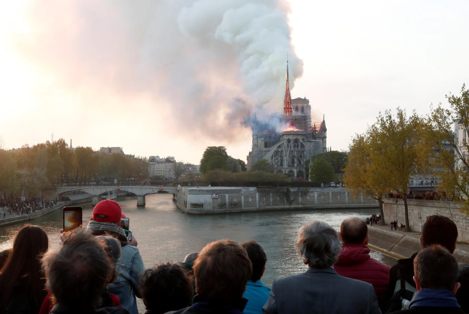 People watch from a bridge as smoke billows from Notre Dame Cathedral during a fire in Paris, France April 15, 2019. (Photo: Benoit Tessier/Reuters)