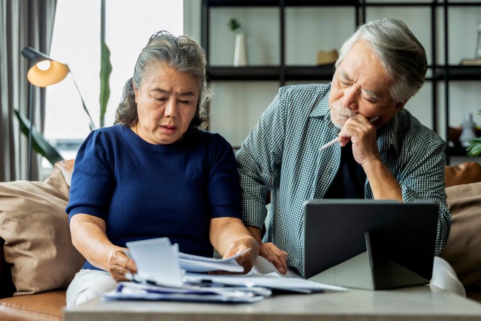 An older couple in their home looking at a document together.