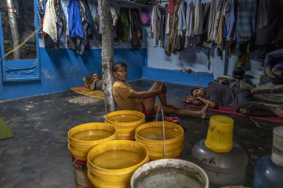 Migrant workers rest beside water containers inside their rented accommodations in Dharavi, one of Asia's largest slums, in Mumbai, India, Friday, May 5, 2023. The Indian government has promised that every legal household will soon have plumbing and running water - a goal set for this year that has yet to be reached. "But just because we spend money and put the pipes in, doesn't mean that people will actually have water in their taps," one Indian water expert says. (AP Photo/Dar Yasin)