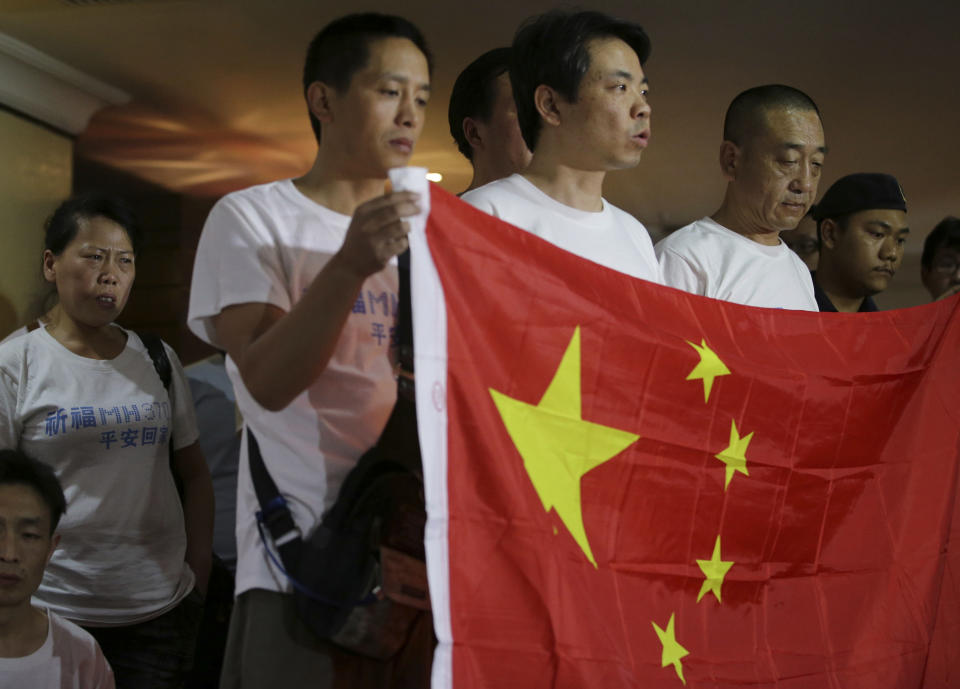 A teary-eyed Chinese woman listens from the back as other relatives of passengers on board the missing Malaysian Airlines MH370 flight speak to reporters while they hold a Chinese flag at a hotel in Subang Jaya, Malaysia, Sunday March 30, 2014. Several dozen Chinese relatives of passengers on Flight 370 arrived in Malaysia Sunday to demand more information about what happened to the airliner that has been missing for more than three weeks, saying there has not been enough information on what happened to their loved ones. (AP Photo/Aaron Favila)