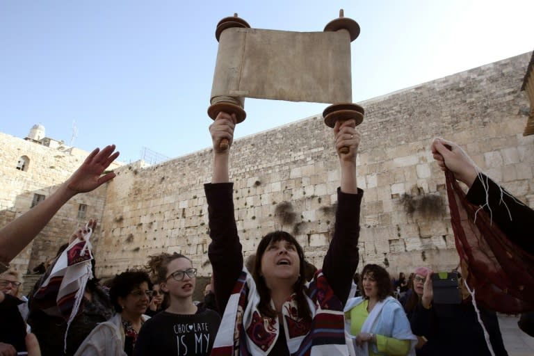 A member of the liberal Jewish religious group Women of the Wall wears a "Tallit", a Jewish prayer shawl traditionally worn by men, as she holds up a Torah scroll at the Western Wall on March 11, 2016