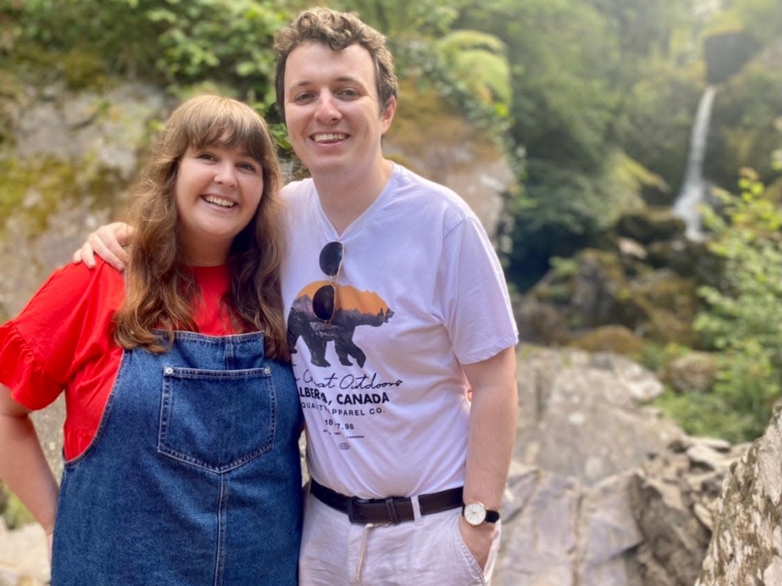 alexis and her partner posing in front of a waterfall