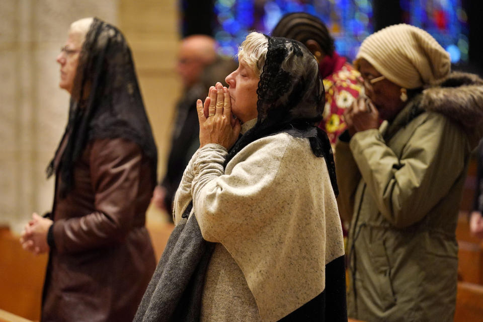 Pam Rousseau, center, and other worshippers pray during a service at the Basilica of Saints Peter and Paul, Sunday, Oct. 29, 2023, in Lewiston, Maine. The community is working to heal following shooting deaths of 18 people at a bowling alley and a bar in Lewiston on Wednesday. (AP Photo/Robert F. Bukaty)