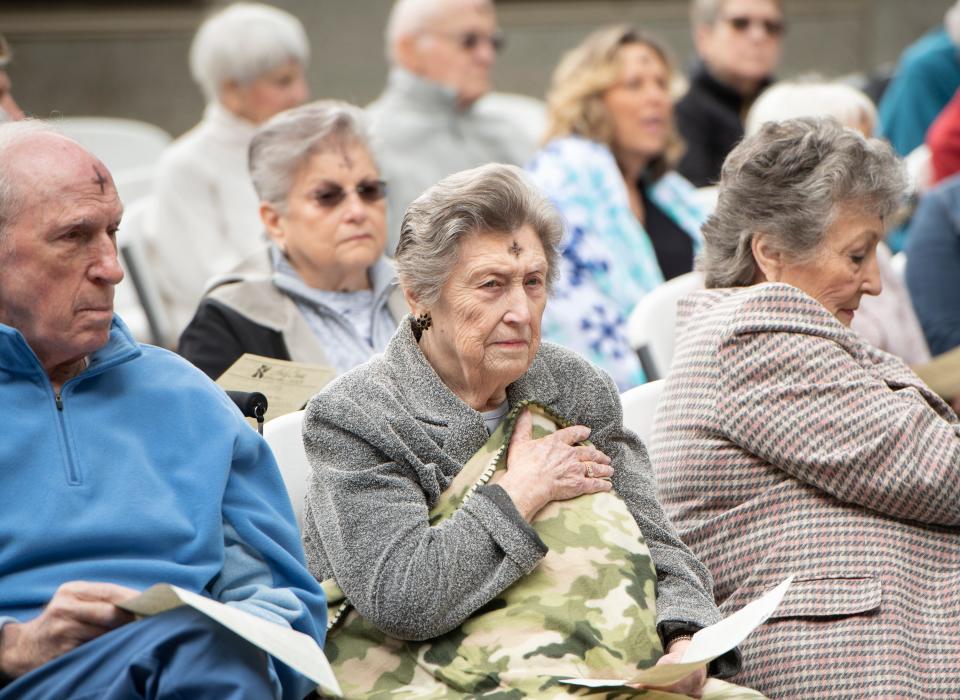 Marilyn Sanchez, center, tries to keep warm during the chily outdoor Ash Wednesday service at Holy Cross Episcopal Church in Pensacola on Wednesday, Feb. 26, 2020.