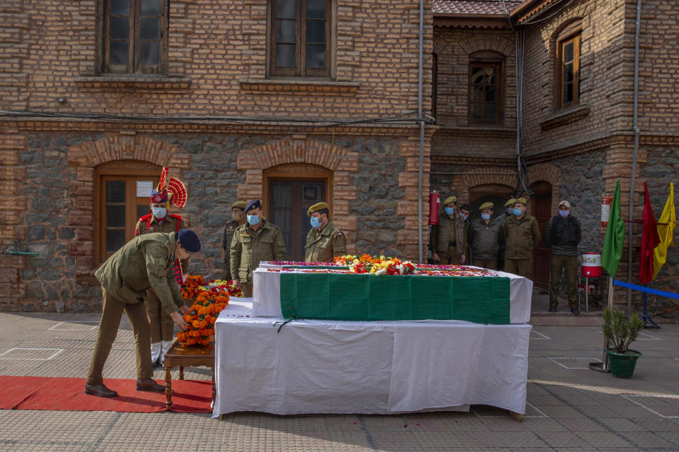 An Indian police officer lays a wreath as he pays respect to colleagues killed in an attack in Srinagar, Indian controlled Kashmir, Friday, Feb. 19, 2021. Anti-India rebels in Indian-controlled Kashmir killed two police officers in an attack Friday in the disputed region's main city, officials said. Elsewhere in the Himalayan region, three suspected rebels and a policeman were killed in two gunbattles. (AP Photo/ Dar Yasin)