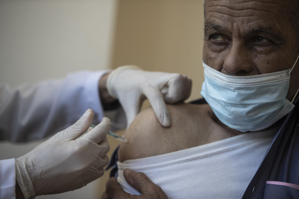 A Palestinian man receives a shot of the Russian-made Sputnik V coronavirus vaccine, at an UNRWA clinic in Gaza City, Wednesday, March 17, 2021. The Palestinian Authority says it will receive 62,000 coronavirus vaccine doses through a World Health Organization partnership designed to help poor countries. (AP Photo/Khalil Hamra)