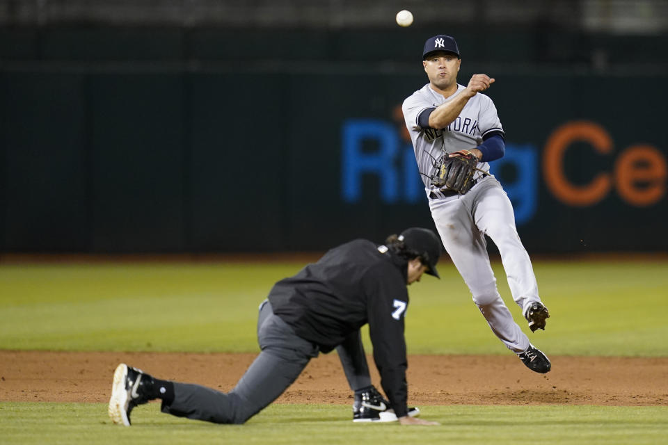 Umpire Brian O'Nora (7) ducks as New York Yankees shortstop Isiah Kiner-Falefa (12) throws to first base for an out against Oakland Athletics' Vimael Machín during the fifth inning of a baseball game in Oakland, Calif., Thursday, Aug. 25, 2022. (AP Photo/Godofredo A. Vásquez)