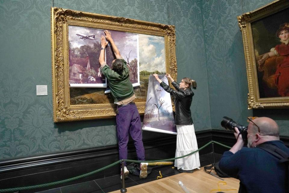 Protesters from Just Stop Oil cover John Constable's The Hay Wain with their own picture at the National Gallery (PA)