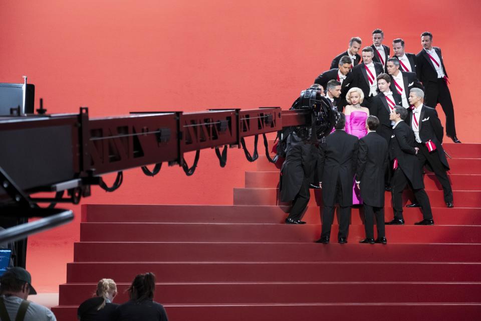 A woman surrounded by men sings on stairs