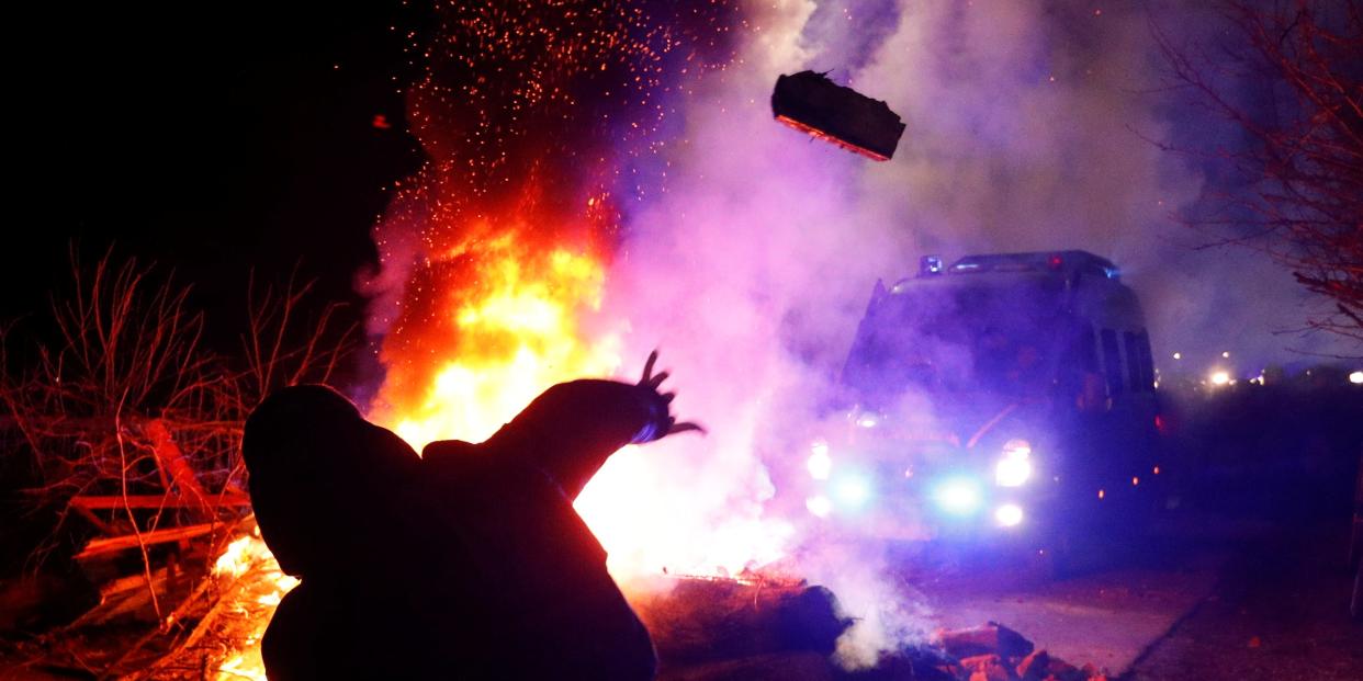 A demonstrator throws a stone towards a police van during a protest against the arrival of a plane carrying evacuees from coronavirus-hit China's Hubei province in the village of Novi Sanzhary in Poltava region, Ukraine February 20, 2020. Local residents blocked the road leading to a sanatorium where the evacuees are due to be held in quarantine for at least two weeks. REUTERS/Valentyn Ogirenko