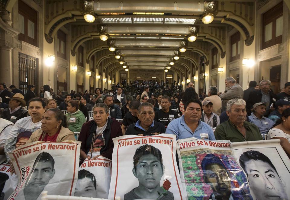 Family members hold posters that show images of their missing sons, during a signing ceremony at the National Palace in Mexico City, on Monday, Dec. 3, 2018. Mexico's new President Andres Manuel Lopez Obrador signed a decree creating a truth commission to investigate the 2014 disappearance of 43 students from the Ayotzinapa teachers college in an apparent massacre in the Mexican state of Guerrero. (AP Photo/Christian Palma)