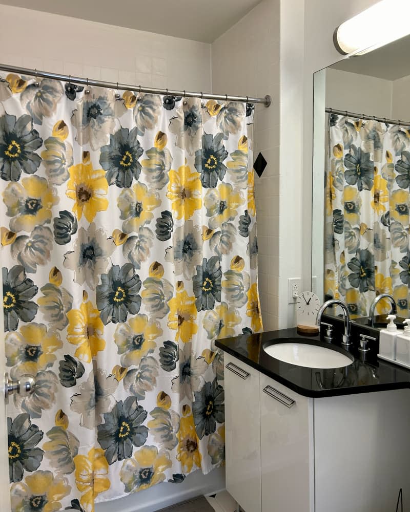 Black vanity countertop in bathroom with floral shower curtain.
