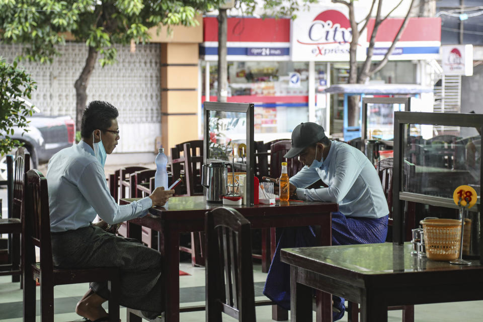 Customers sitting behind mirror aluminum frame to help curb the spread of the new coronavirus, use their mobile at a tea-shop in Yangon, Myanmar Monday, May 18, 2020. (AP Photo/Thein Zaw)