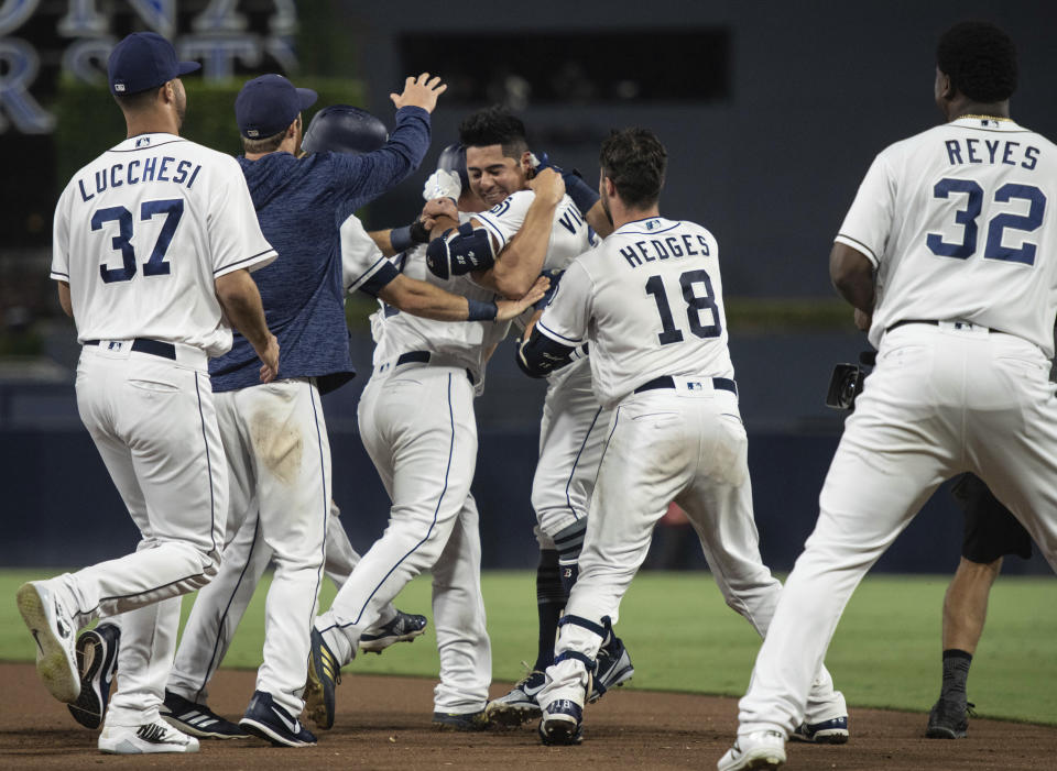 San Diego Padres celebrate after Christian Villanueva, center right, hit a walk-off single against the Arizona Diamondbacks during a baseball game in San Diego, Saturday, Aug. 18, 2018. The Padres won 7-6. (AP Photo/Kyusung Gong)