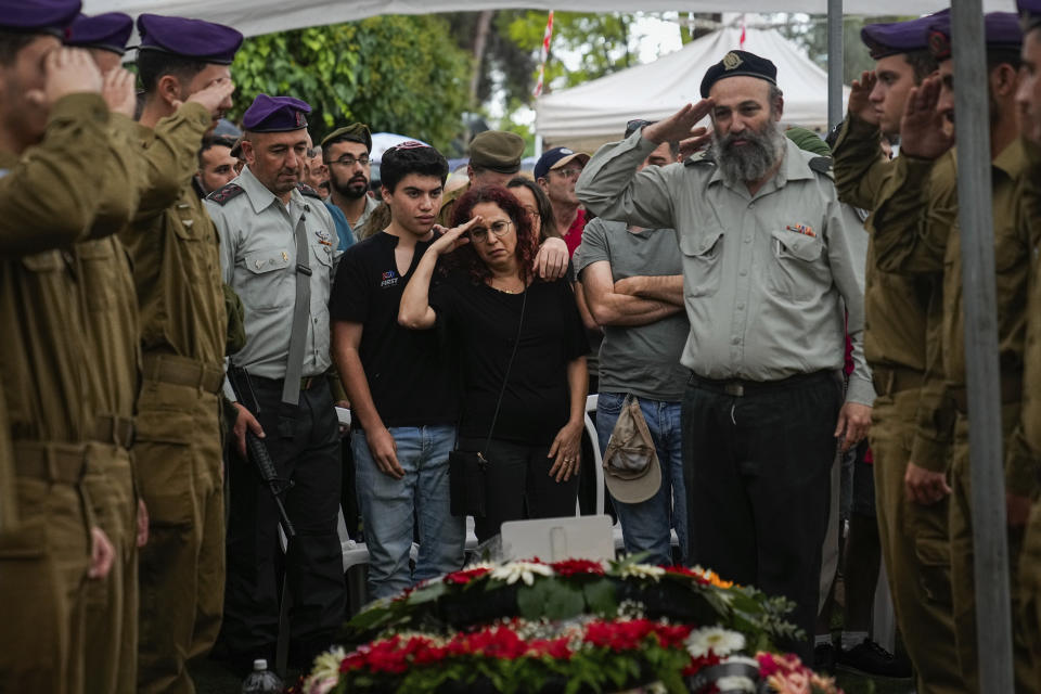Israeli soldiers and Shlomit Lipshitz, center, mother of Staff Sgt. Lavi Lipshitz salutes over her son's grave during his funeral in the Mount Herzl Military Cemetery in Jerusalem, Wednesday, Nov. 1, 2023. Lipshitz was killed during a ground operation in the Gaza Strip. Israeli ground forces have been operating in Gaza in recent days as Israel presses ahead with its war against Hamas militants. (AP Photo/Ohad Zwigenberg)