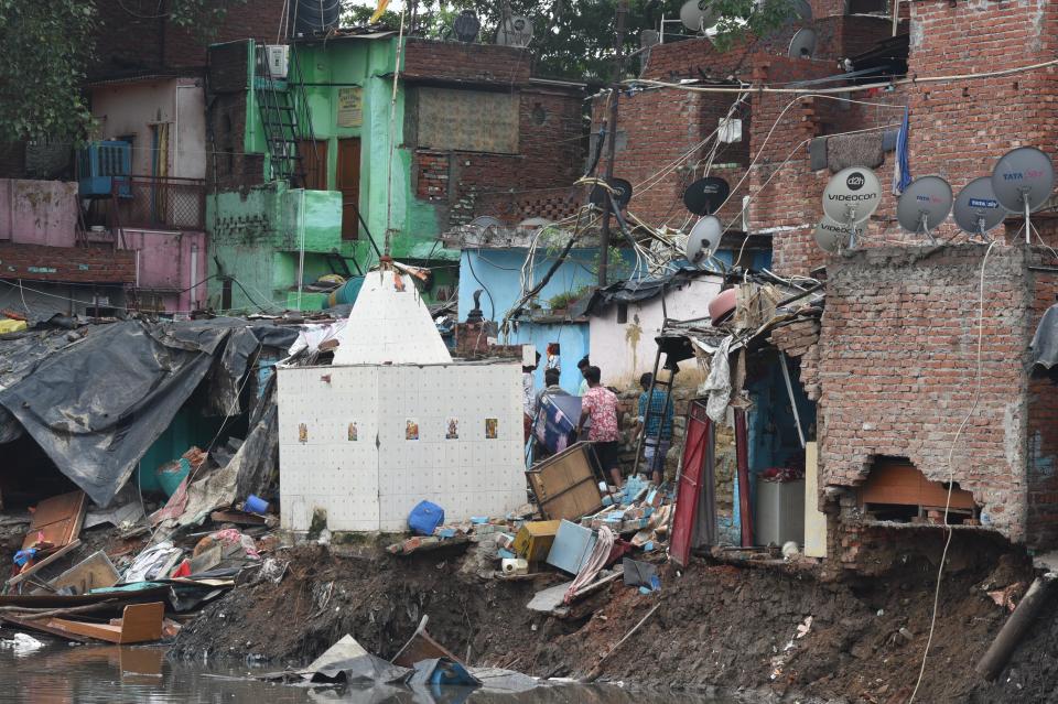 People try to salvage their belongings from an area in Anna Nagar where several houses collapsed due to heavy rain and were swept into a canal, on July 19, 2020 in New Delhi, India. Moderate-to-heavy rain lashed several states in northern, eastern and coastal India on Sunday, but the monsoon activity continued to remain subdued in Delhi, which has recorded a 40 per cent rainfall deficiency despite an early onset of the seasonal weather system. (Photo By Sonu Mehta/Hindustan Times via Getty Images)