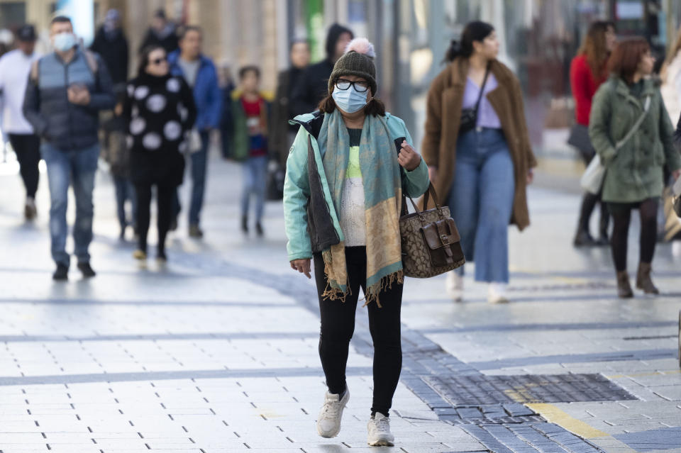 CARDIFF, WALES - DECEMBER 26: A shopper wears a face mask in the city centre on December 26, 2021 in Cardiff, Wales. A revised version of alert level two measures was introduced today at 6am to help mitigate the spread of the Omicron coronavirus variant. (Photo by Matthew Horwood/Getty Images)