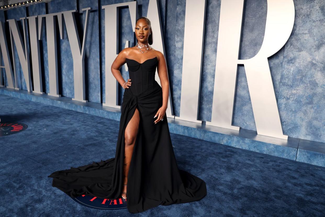 A woman in a strapless black gown with a high slit