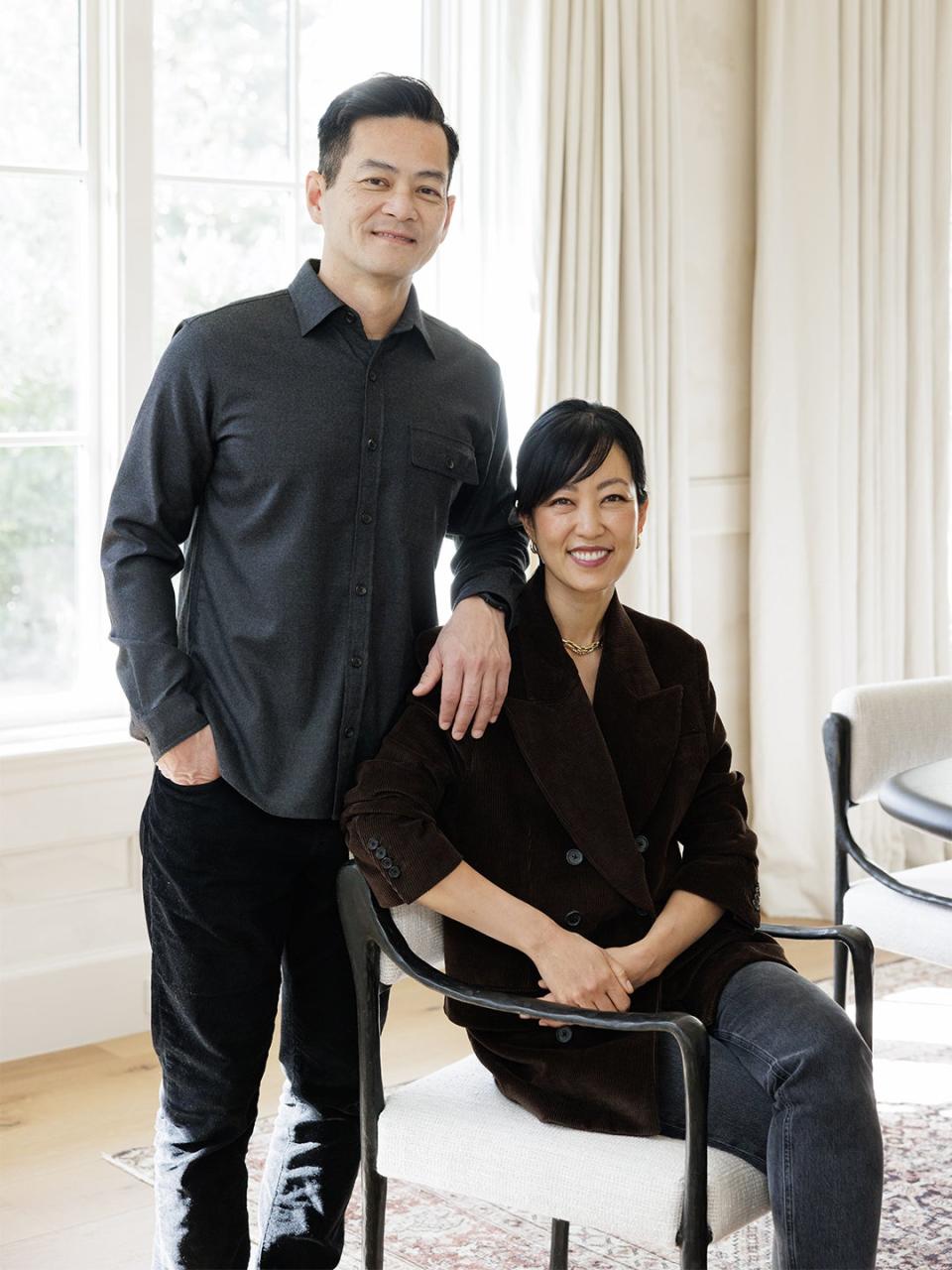 Couple seated in their home with white window treatments