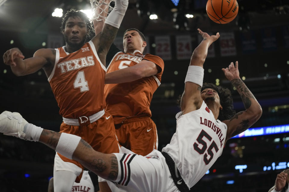 Louisville's Skyy Clark, right, tries to make a shot while falling as Texas's Tyrese Hunter, left, and Kadin Shedrick guard during the first half of an NCAA college basketball game, Sunday, Nov. 19, 2023, in New York. (AP Photo/Seth Wenig)