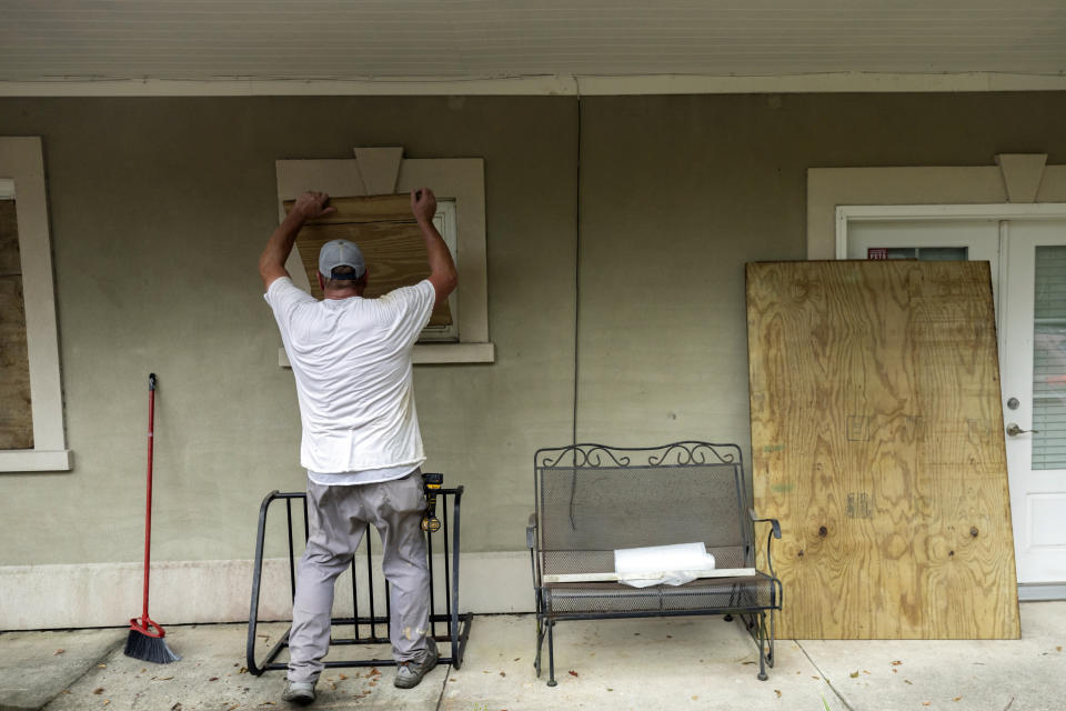 Bryan Moore ayuda a su amigo a tapiar su casa en la isla Tybee, en Georgia, el martes 29 de agosto de 2023, previo a la llegada del huracán Idalia. (Stephen B. Morton/Atlanta Journal-Constitution vía AP)
