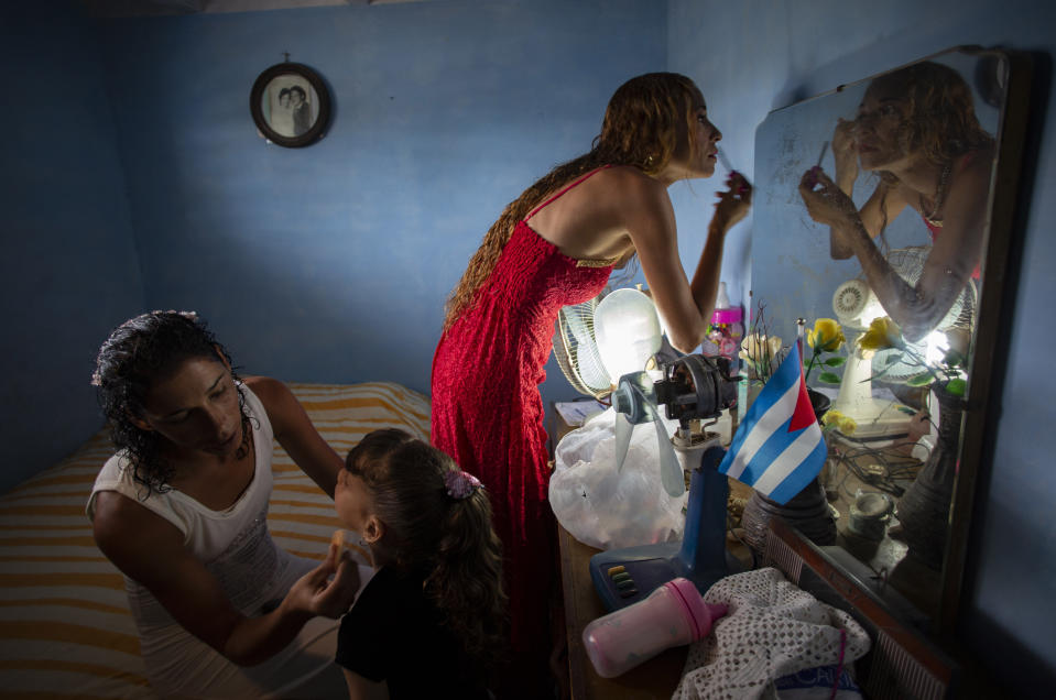 Liusba Grajales, a la izquierda, maquilla a su hija Ainhoa ​​mientras su pareja Lisset Díaz Vallejo se prepara para casarse en Santa Clara, Cuba, el viernes 21 de octubre de 2022. (AP Foto/Ismael Francisco)