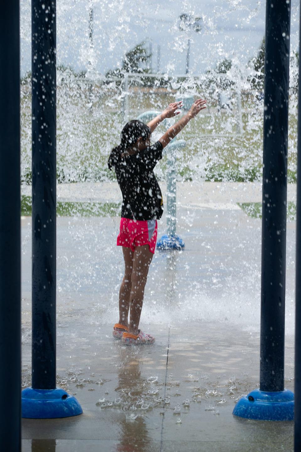 Arabella Cardona, 10, stands under a large bucket as it pours water down on her at the Salinas Park Splash Pad Thursday, July 6, 2023.