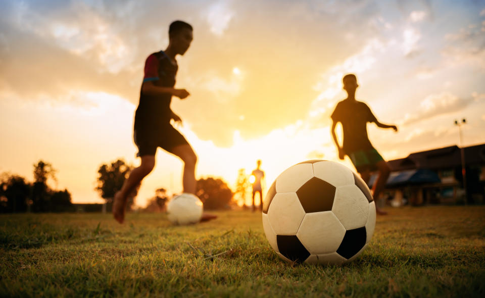 A group of kids having fun playing soccer football on the dirt field. (PHOTO: Getty Images)