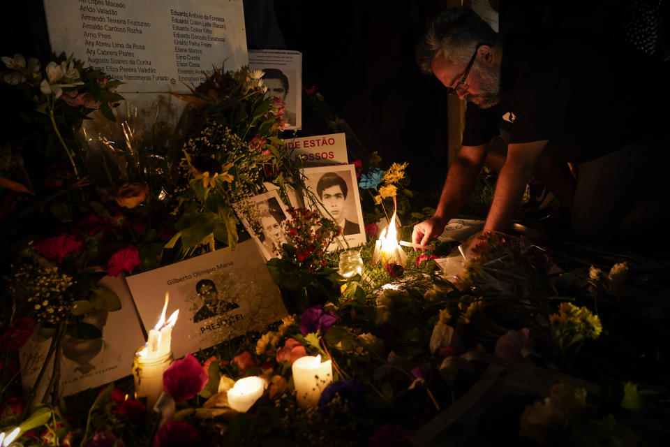 A person places a candle in an altar for victims of Brazil's dictatorship in Sao Paulo, Brazil, Sunday, March 31, 2019. Thousands of demonstrators took to the streets in several major Brazilian cities Sunday to protest the 55th anniversary of the coup that instituted the country's 1964-1985 military regime. (AP Photo/Victor R. Caivano)