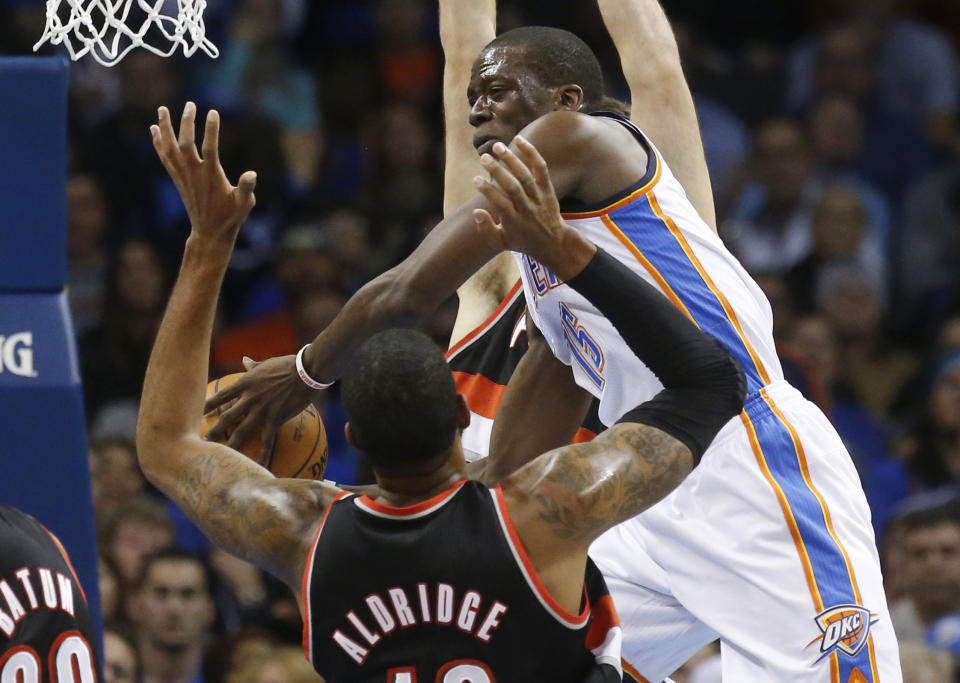 Oklahoma City Thunder guard Reggie Jackson, right, drives past Portland Trail Blazers forward LaMarcus Aldridge (12) in the first quarter of an NBA basketball game in Oklahoma City, Tuesday, Jan. 21, 2014. (AP Photo/Sue Ogrocki)