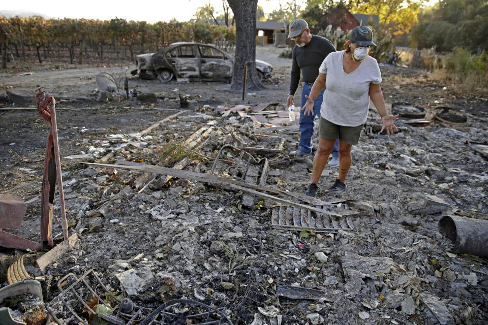 Justo and Bernadette Laos look through the charred remains of the home they rented that was destroyed by the Kincade Fire near Geyserville, Calif., Thursday, Oct. 31, 2019. (AP Photo/Charlie Riedel)