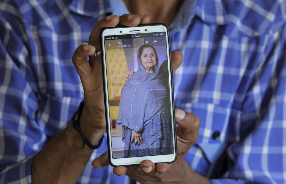 Pakistani Shahid Ahmed shows the picture of his mother Irshad Begum, who was killed in the Friday's plane crash, on his mobile phone outside a morgue in Karachi, Pakistan, Saturday, May 23, 2020. An aviation official says a passenger plane belonging to state-run Pakistan International Airlines carrying passengers and crew has crashed near the southern port city of Karachi. (AP Photo/Fareed Khan)