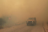 A Lebanese army vehicle drives past flames of a forest fire, at Qobayat village, in the northern Akkar province, Lebanon, Thursday, July 29, 2021. Lebanese firefighters are struggling for the second day to contain wildfires in the country's north that have spread across the border into Syria, civil defense officials in both countries said Thursday. (AP Photo/Hussein Malla)