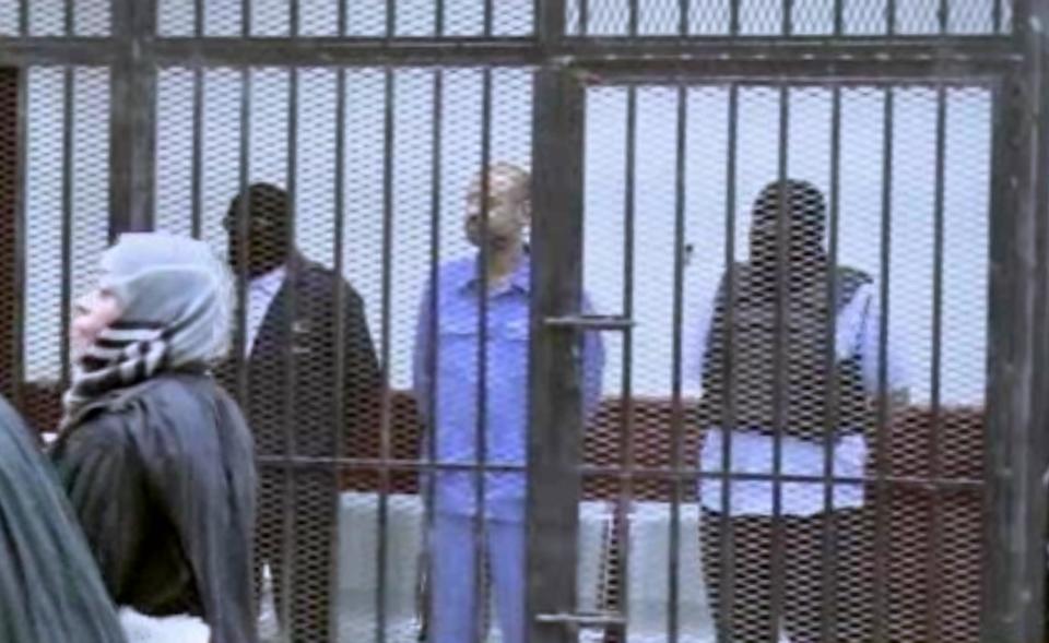 FILE - This image Thursday, Sept. 19, 2013 file photo made from AP video shows Seif al-Islam Gadhafi, son of Libya's former dictator Moammar Gadhafi, inside a cage in a courtroom in Zintan, Libya. A Libyan judge in the trial of former regime officials has decided that Moammar Gadhafi's son, held by a militia in the country's west, can attend the proceedings through a video link. Since the end of Libya's 2011 civil war, Seif al-Islam Gadhafi has been held by a militia in Zintan, which has refused to hand him over for a separate trial in the capital, Tripoli — a sign of the central government's weakness. Al-Islam faces charges along with 39 other Gadhafi regime figures — including notorious spymaster Abdullah al-Senoussi — for alleged crimes during Libya's conflict.(AP Photo via AP video, File)