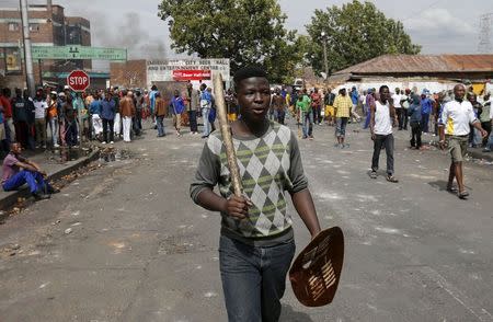 A local gestures as he holds a stick and a shield outside a hostel during anti-immigrant related violence in Johannesburg, April 17, 2015. REUTERS/Siphiwe Sibeko