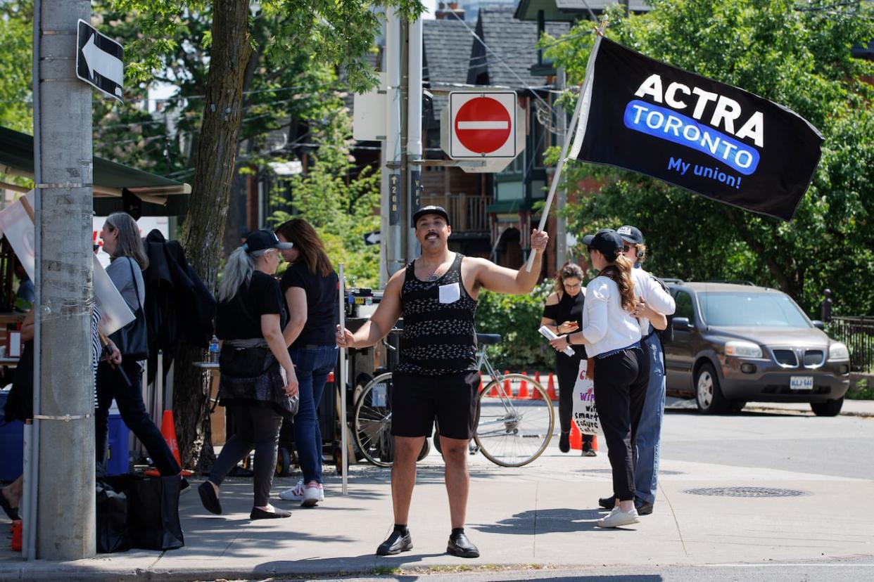 Unionized film workers picket on the set of a commercial being shot in a Toronto restaurant on May 29. Canada's English-language acting union and the organization representing ad agencies have been involved in a dispute since April 2022 around the renegotiation of a deal that sets the rules for using actors in ads. (Evan Mitsui/CBC - image credit)