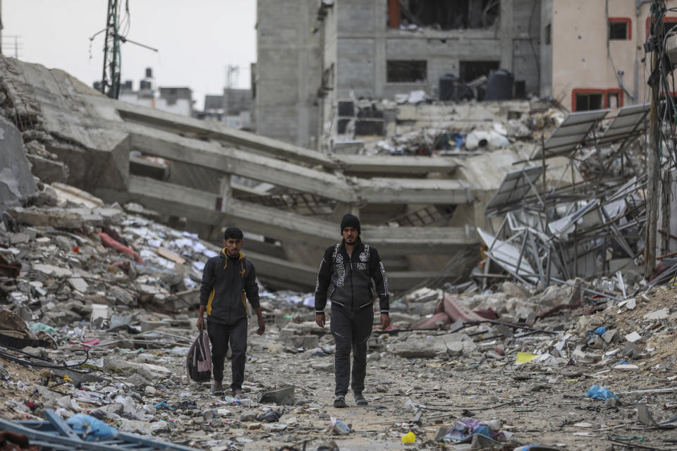 Palestinians walk through destruction in Shati refugee camp on Saturday, Nov. 25, 2023. on the second day of the temporary ceasefire between Hamas and Israel. (AP Photo/Mohammed Hajjar)