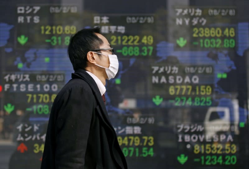 FILE PHOTO: A man walks past an electronic board showing the stock market indices of various countries outside a brokerage in Tokyo, Japan February 9, 2018. REUTERS/Toru Hanai