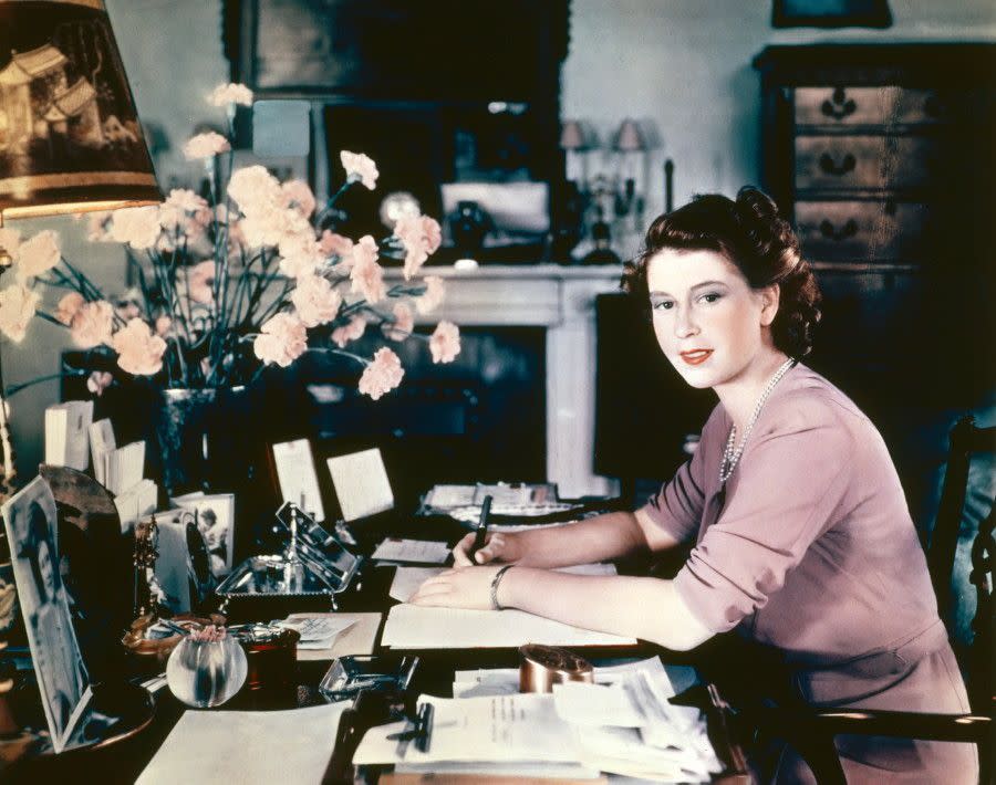 A glamorous Queen Elizabeth II sits at her desk in Buckingham Palace on September 19, 1946.