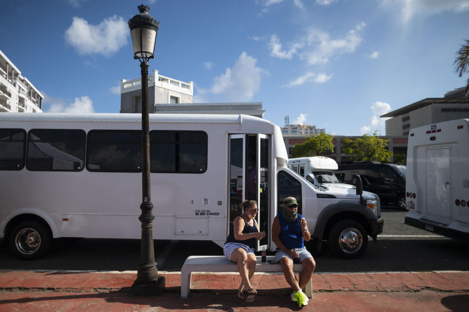 Cruise ship passengers Tom Seuberling, of Florida, and his daughter Shawn, of North Carolina, wait for a tour guide after getting off Carnival's Mardi Gras cruise ship, docked in the bay of San Juan, Puerto Rico, Tuesday, Aug. 3, 2021, marking the first time a cruise ship visits the U.S. territory since the COVID-19 pandemic began. (AP Photo/Carlos Giusti)