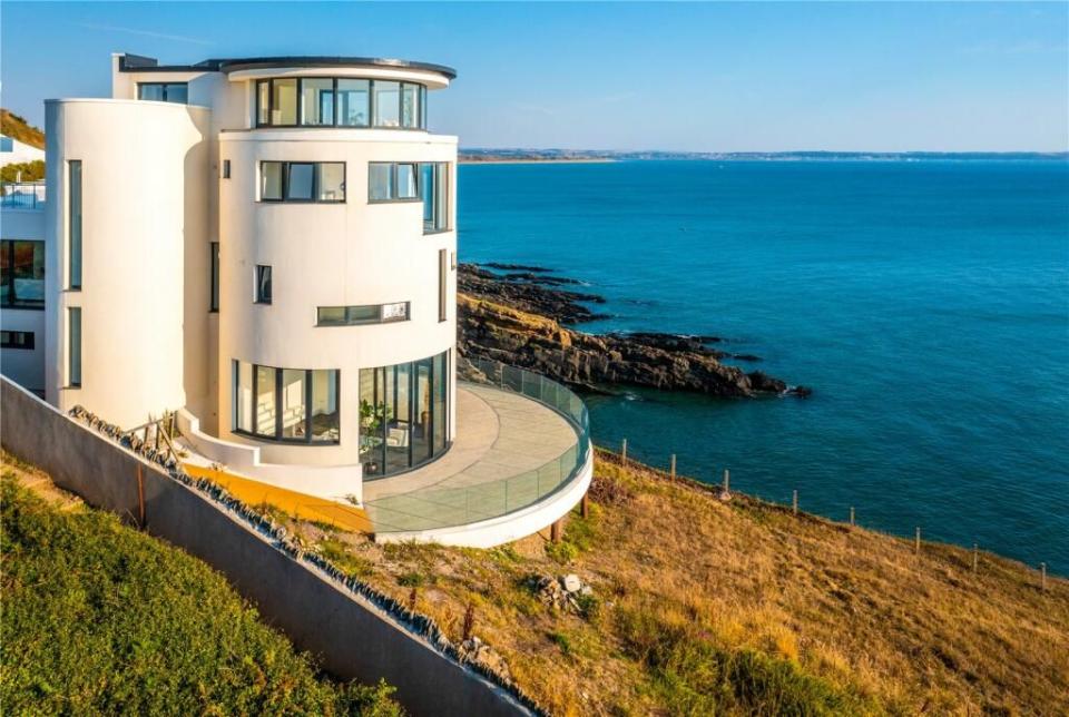 a white building on a cliff above the ocean