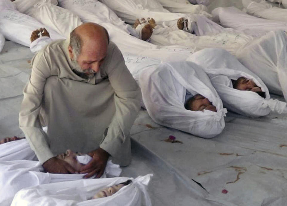 FILE - This Aug. 21, 2013 file citizen journalism image provided by the anti-government Media Office Of Douma City which has been authenticated based on its contents and other AP reporting, shows a Syrian man mourning over a dead body after an alleged poisonous gas attack fired by government forces, according to activists, in Douma town, Damascus, Syria. Syria denies ever using chemical weapons during the war and says it eliminated its chemical arsenal under a 2013 agreement brokered by the U.S. and key ally Russia. It also joined the Hague-based global chemical weapons watchdog as global pressure mounted on Damascus. (Media Office Of Douma City via AP, File)