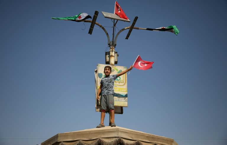 A Syrian child waves the flag of key rebel backer Turkey at anti-government demonstration in the Idlib town of Hazzanu on September 21, 2018