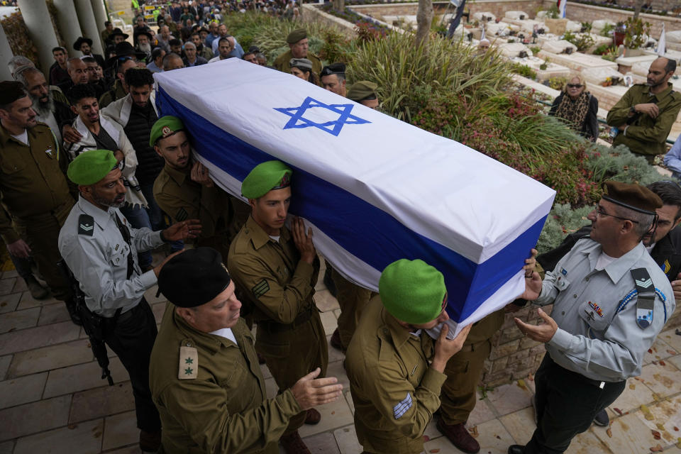 Israeli soldiers carry the flagged covered coffin of Sergeant Lavi Ghasi as family and friends follow during his funeral in Modiin, Israel,Thursday, Dec. 21, 2023. Ghasi ,19, was killed during the Israeli military's ground operation in the Gaza Strip. while the army is battling Palestinian militants in the war ignited by Hamas' Oct. 7 attack into Israel. (AP Photo/Ariel Schalit)