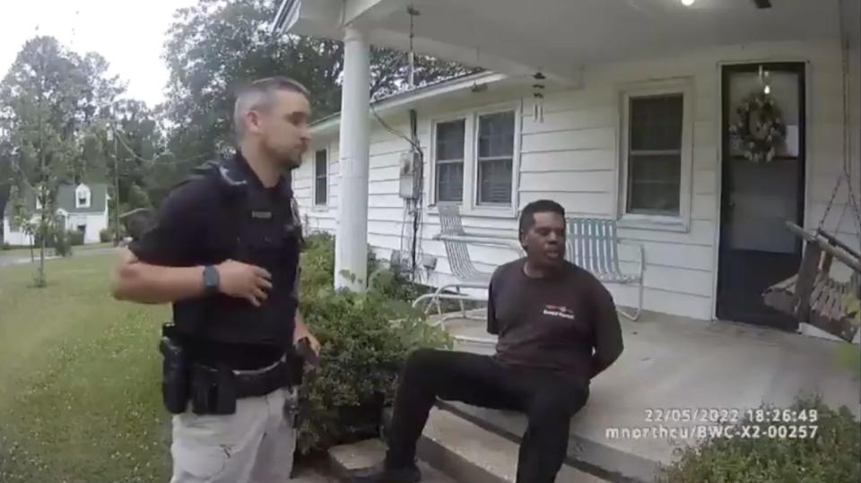 Michael Jennings in handcuffs sitting on the front steps of the house he was watering flowers at.