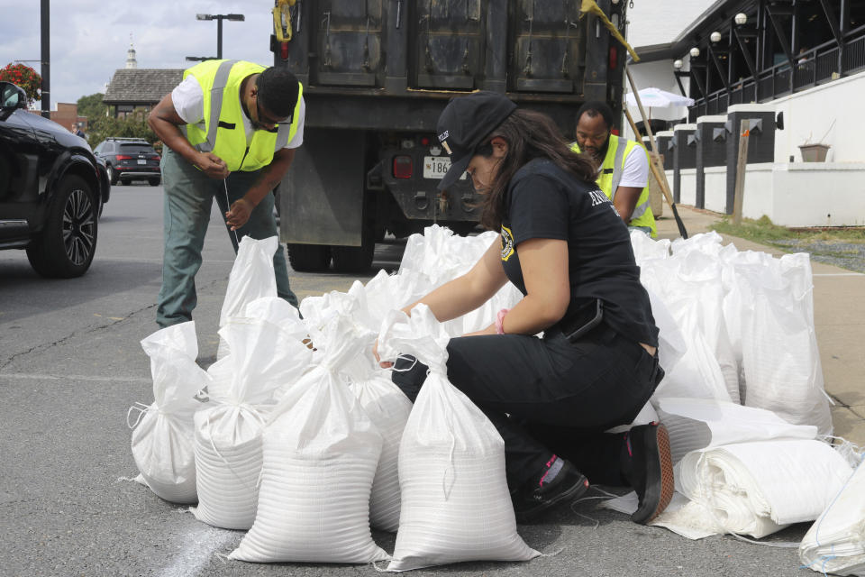 Nicole Torres, a spokeswoman for the Office of Emergency Management for the city of Annapolis, Md., ties a sandbag on Friday, Sept. 22, 2022 as residents prepared for an approaching storm. (AP Photo/Brian Witte)