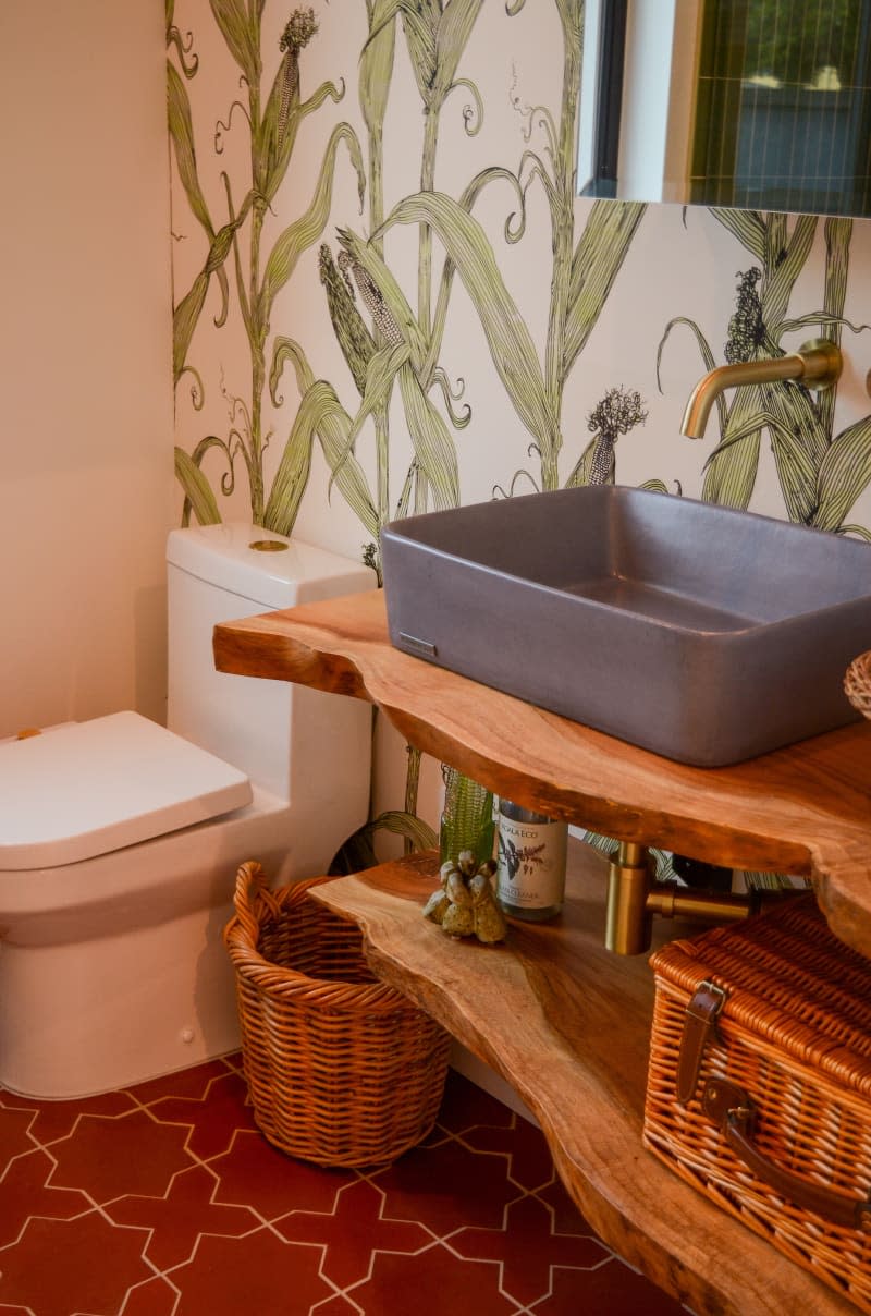 Corner view of bathroom with live wood shelves and corn wallpaper.