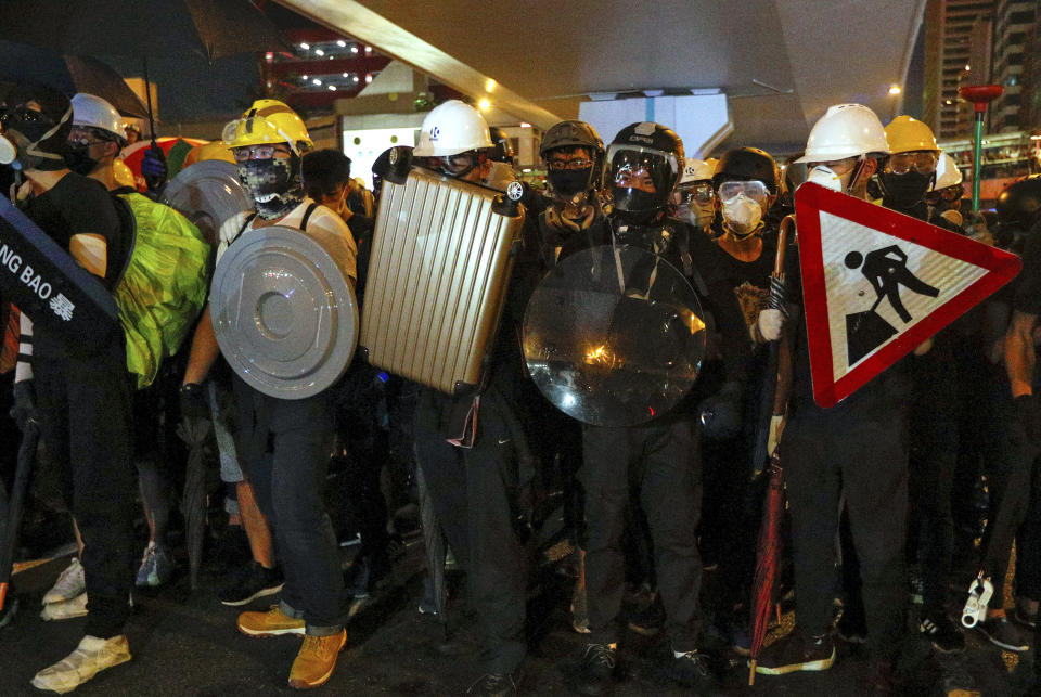 Protesters carrying home-made shields face off with riot policemen on a street in Hong Kong, Sunday, July 21, 2019. Hong Kong police have thrown tear gas canisters at protesters after they refused to disperse. Hundreds of thousands of people took part in a march Sunday to call for direct elections and an independent investigation into police tactics used during earlier pro-democracy demonstrations. Police waved a black warning flag Sunday night before lobbing the canisters into a crowd of protesters. (AP Photo/Bobby Yip)